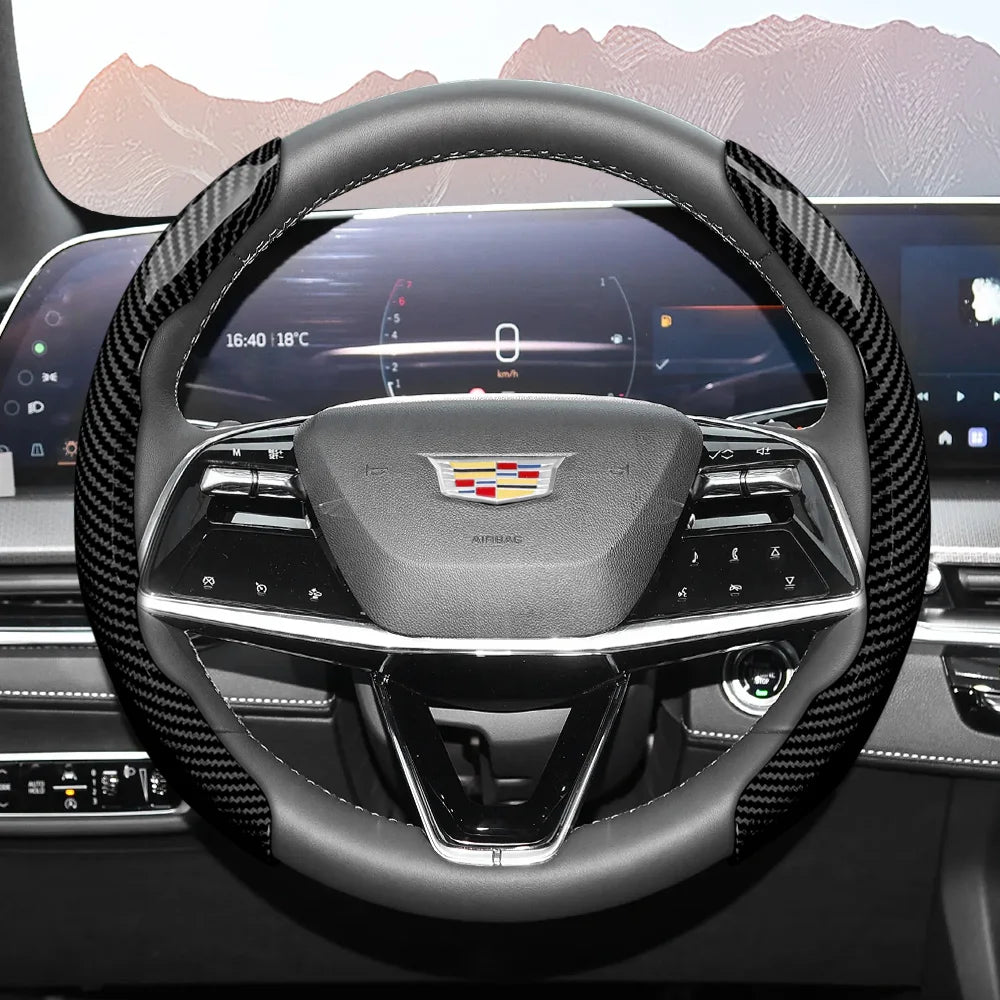 A close-up view of a black steering wheel with a carbon fiber grip and an airbag cover.