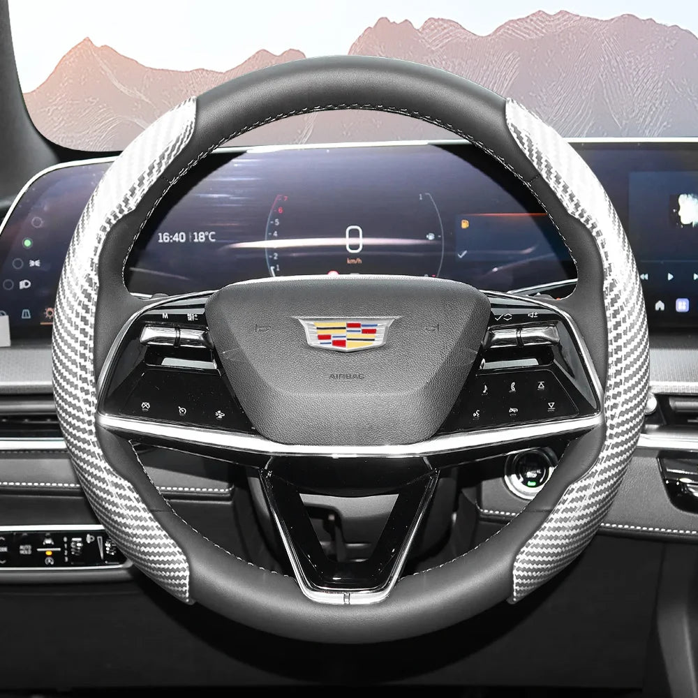 Close-up view of a black steering wheel with a patterned carbon fiber cover inside a modern car interior.