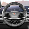 Close-up view of a black steering wheel with a patterned carbon fiber cover inside a car interior.