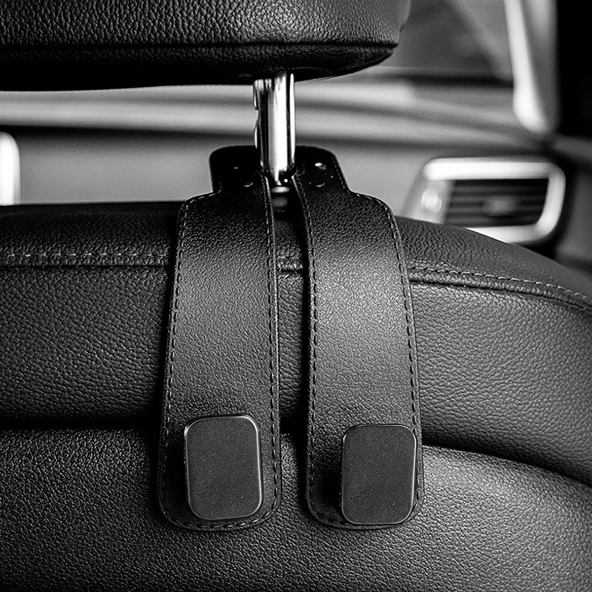 Close-up of black car seat headrest hooks used for vehicle organization.