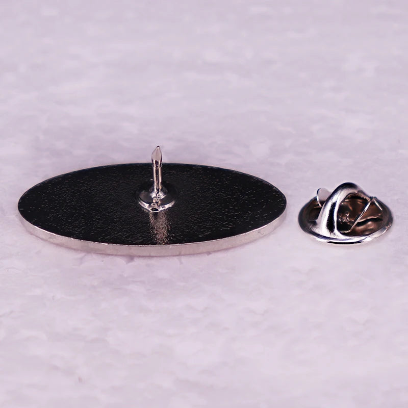 A silver oval emblem pin brooch for a Peterbilt truck, showing the back mechanism.