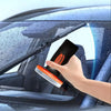 A hand is using a handheld glass emulsion oil film remover to clean the exterior of a car window.