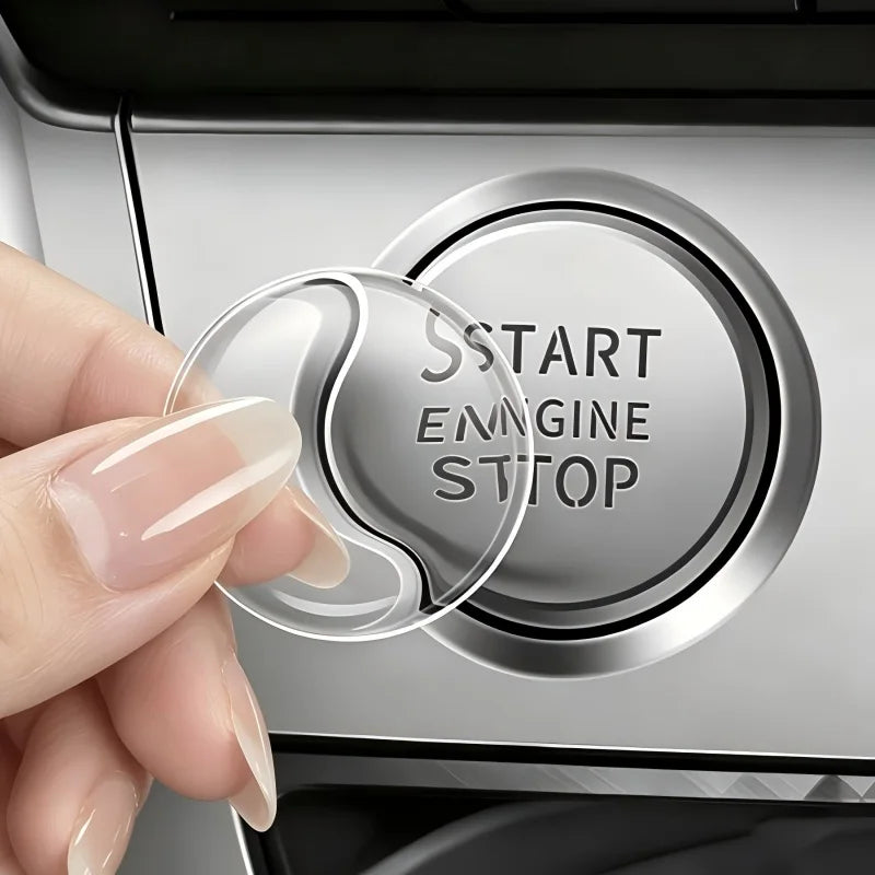A hand presses a crystal clear ignition button protector on a car's start engine stop switch.