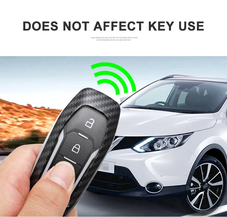 A hand holds a black carbon fiber car key cover next to a white car.