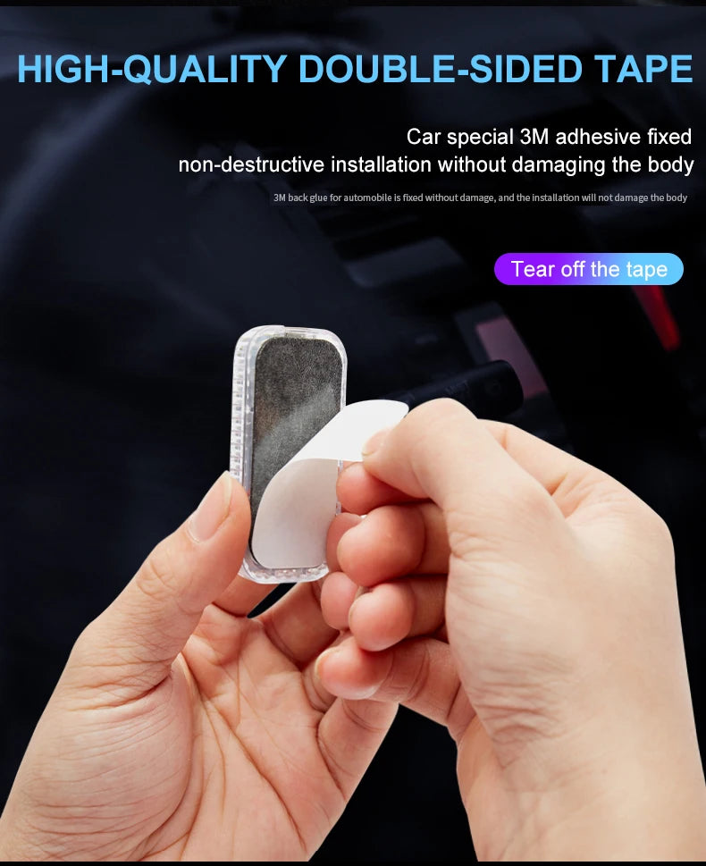 Hands are peeling a piece of double-sided tape from a car interior surface for installation.