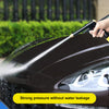 A hand is using a high-pressure water gun to clean the exterior of a dark car.
