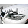 Close-up of a white car headlight with a black eyelash sticker set installed.