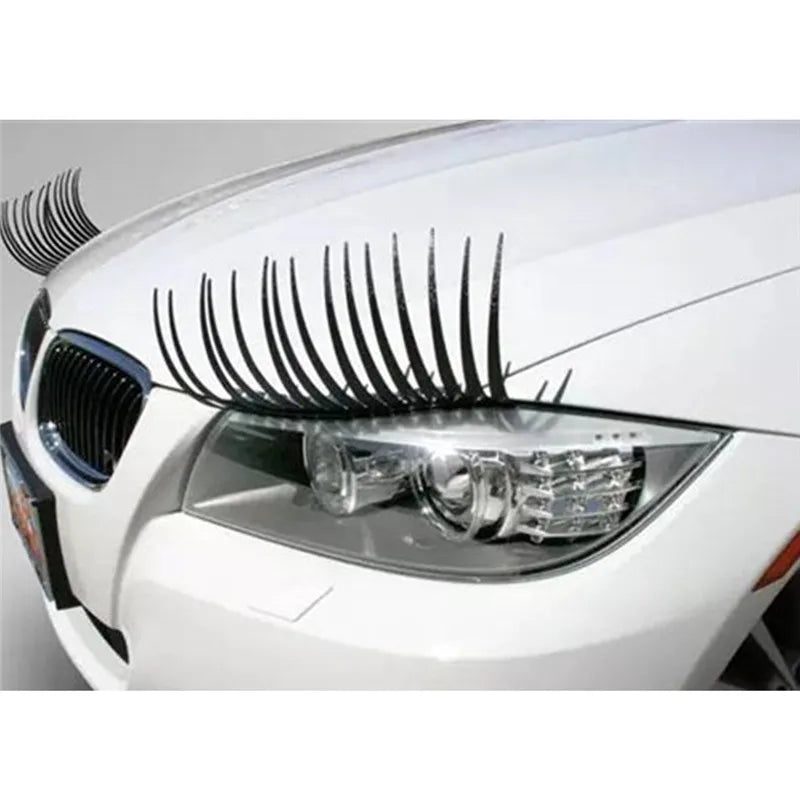 Close-up of a white car headlight with a black eyelash sticker set installed.