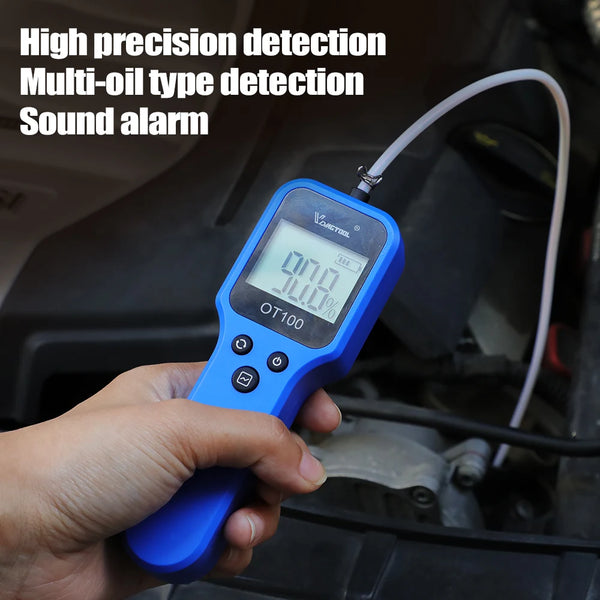 A hand holds a blue digital engine and brake fluid tester device near a vehicle engine component.
