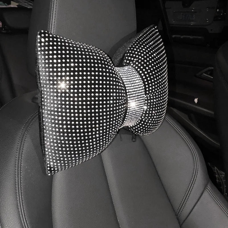 Primer plano de un cojín para el cuello de coche de pedrería cristalina con diseño de lazo sobre un asiento de cuero oscuro.