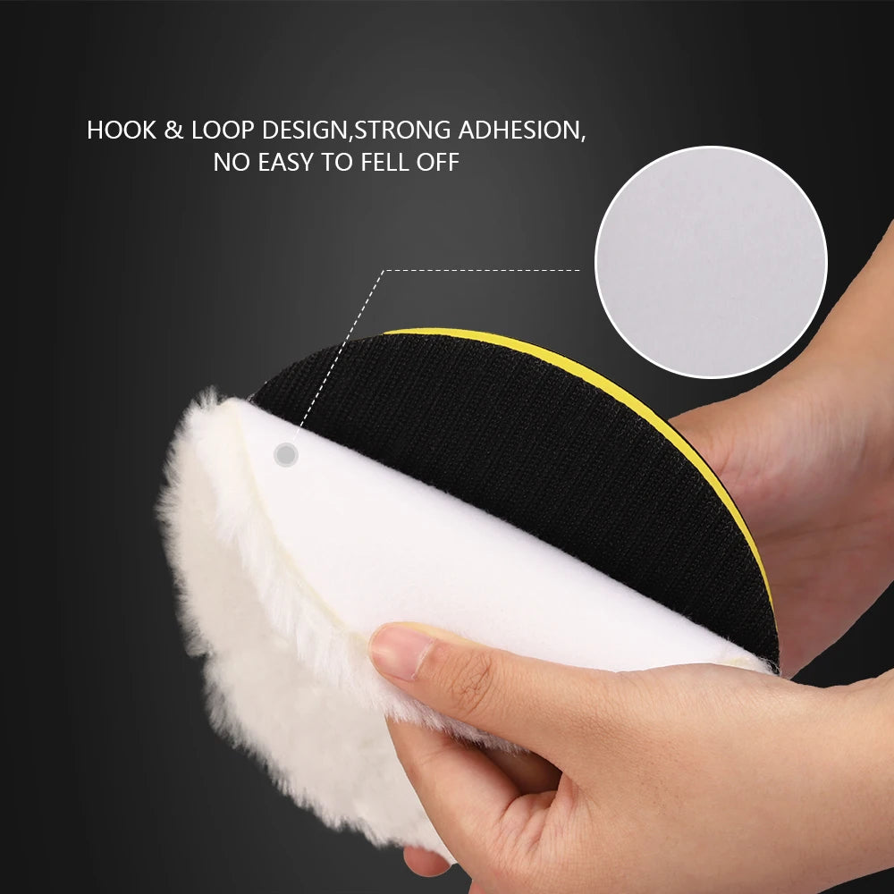 A hand is holding a black and white wool polishing pad with a yellow trim, demonstrating its hook and loop design.