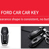 A close-up view of a black carbon fiber car key cover with a silver keyring, resting on a dark surface.