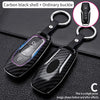 Carbon black shell key cover with ordinary buckle and a separate key fob shown against a dark background