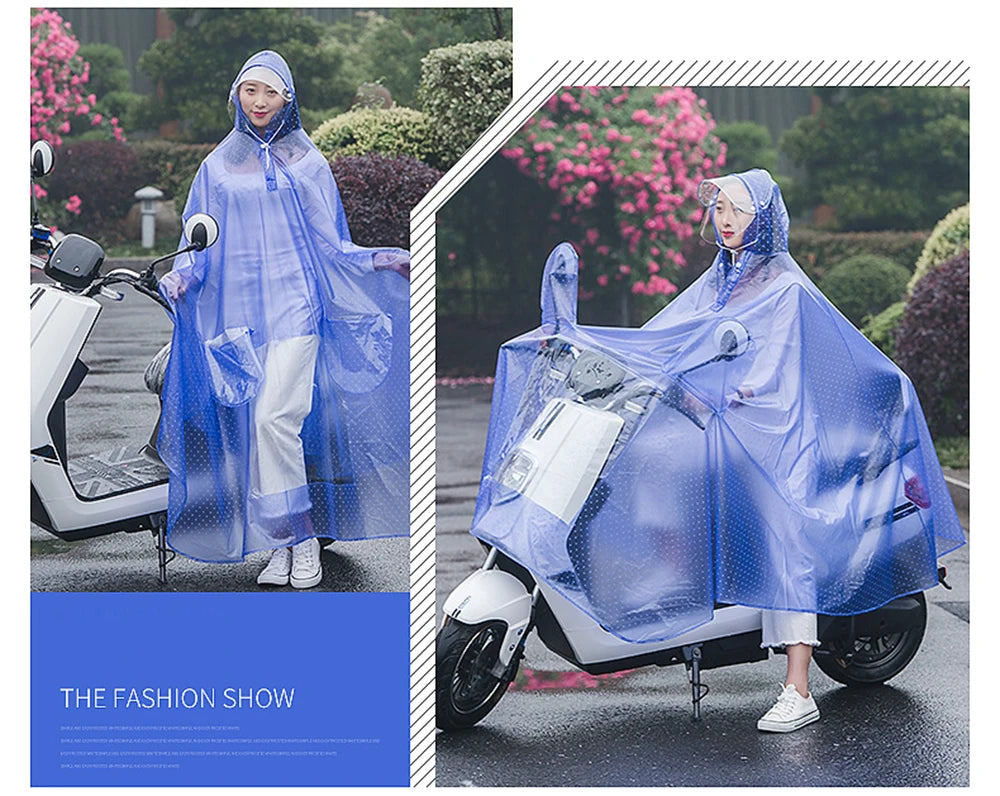 A woman wearing a transparent blue windproof motorcycle rain poncho rides a white scooter in an outdoor setting.