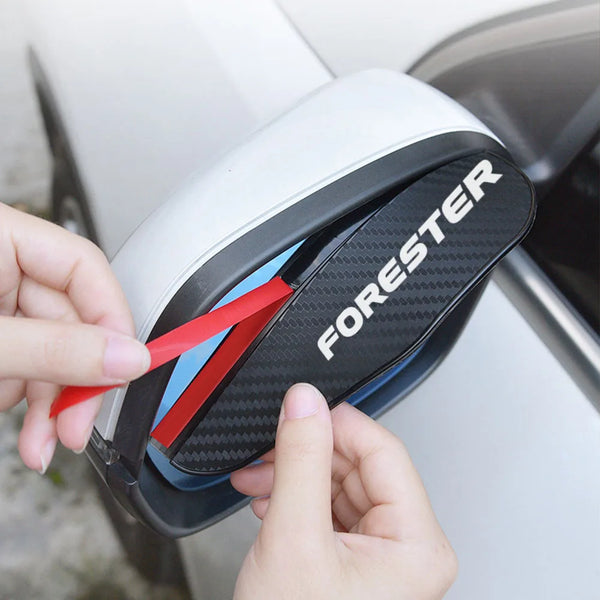 A hand is holding a black and white universal car rain eyebrow product with red accents, demonstrating its fit for a rearview