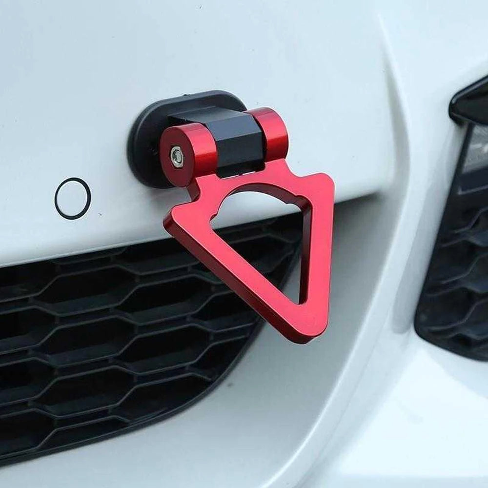 A close-up of a red racing style car tow hook mounted on a white vehicle's grille.