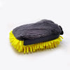 A black microfiber chenille car wash mitt is shown resting on a yellow bristled cleaning brush.