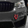 Close-up of a dark gray car's front grille and headlight with a red tow hook accessory installed.