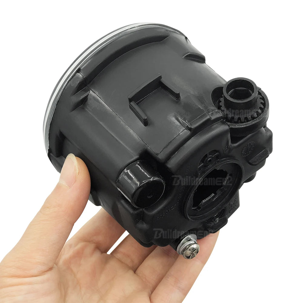 A black halogen fog light kit assembly is held in a hand.