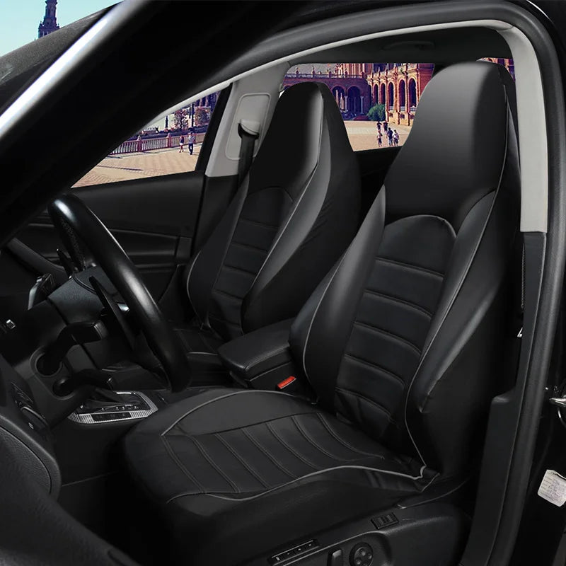 Interior view of a car showing black faux leather seat covers on the front and split bench seats.
