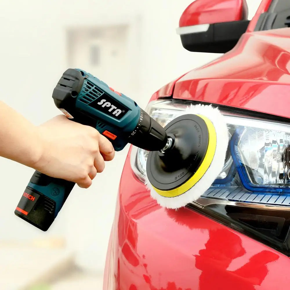A hand is using an SPTA wool polishing pad to buff a red car's headlight.