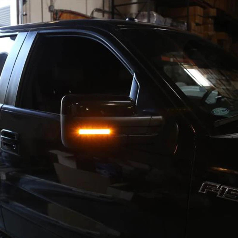 Close-up of amber LED side mirror marker lights on a black Ford F-150 or Raptor.