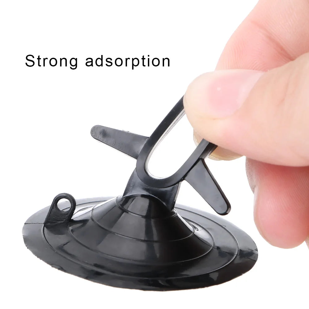 A hand is pressing a black suction cup device onto a smooth surface to demonstrate strong adsorption.