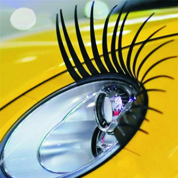 Close-up of a yellow car headlight with black eyelash stickers installed.