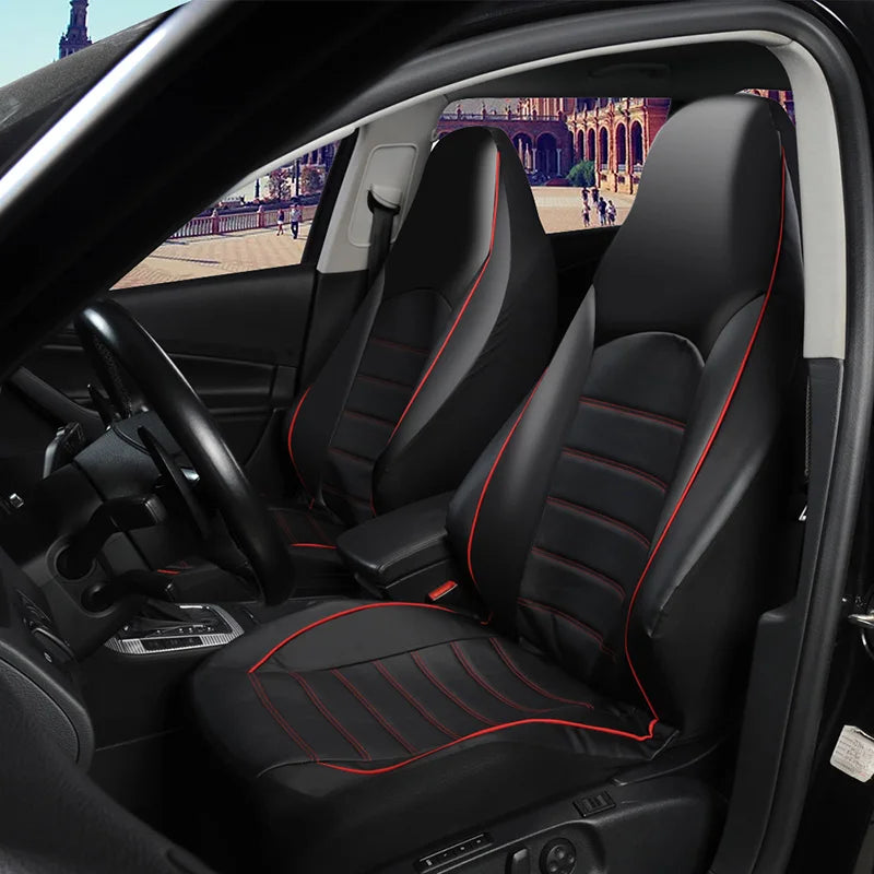 Interior view of a car showing black faux leather seat covers with red stitching on the front and split bench seats.