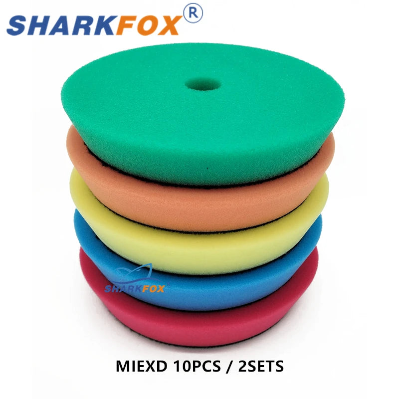 A stack of ten green, orange, yellow, and blue polishing sponge pads for car buffing.
