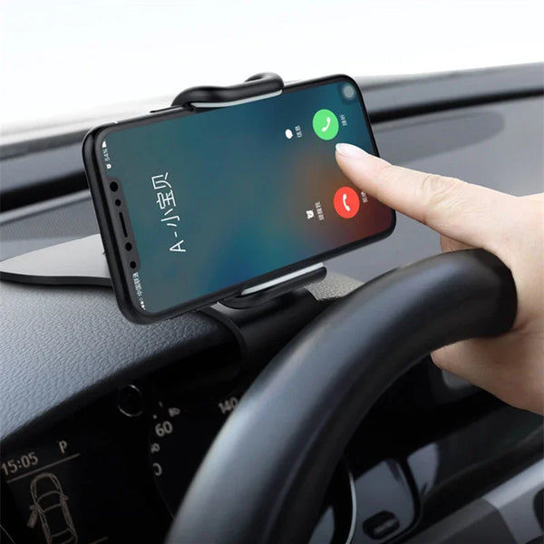 A hand places a smartphone onto a rotating car phone mount installed on a vehicle dashboard.