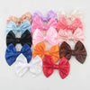 A collection of handmade silk hair bows in various pastel and bold colors including pink, purple, blue, orange, and brown.