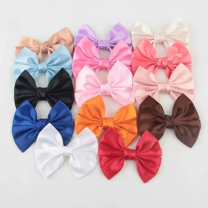 A collection of handmade silk hair bows in various pastel and bold colors including pink, purple, blue, orange, and brown.