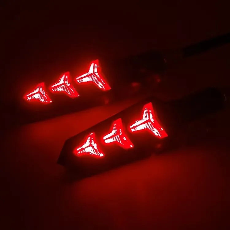 A close-up of flowing red LED motorcycle turn signals illuminating the dark background.