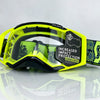 A pair of yellow and black SCOTT safety goggles with a lens lock feature resting on a reflective surface.