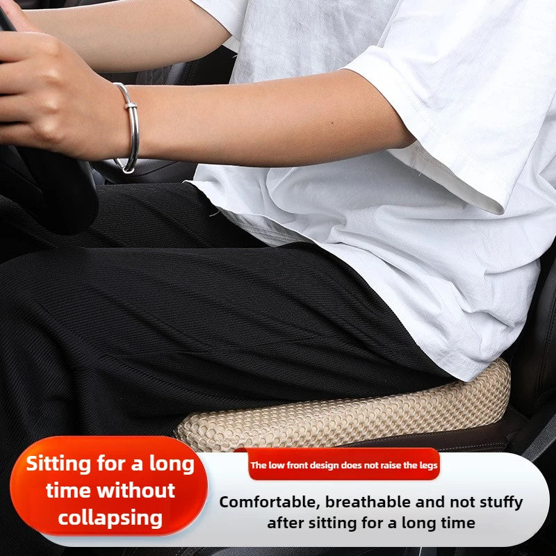 A person is sitting in a car seat with a honeycomb memory foam booster cushion, demonstrating its comfort for long periods.