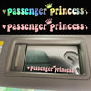 A close-up of a car rearview mirror showing a pink princess sticker on the glass.