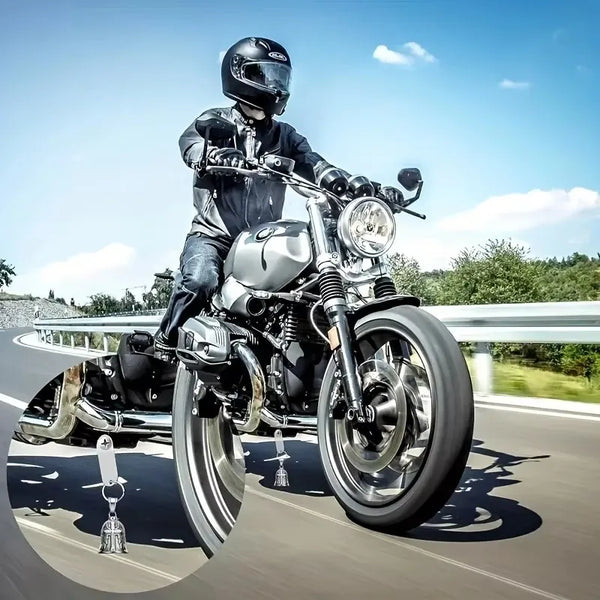 A silver motorcycle with a rider wearing a helmet is shown in motion on a road, featuring a bell and keychain.