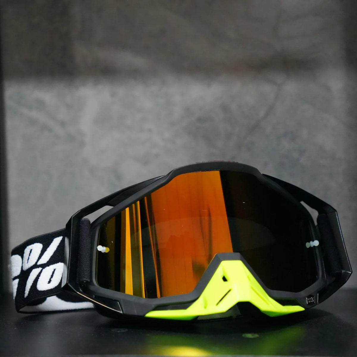A pair of black and neon yellow high-performance motocross goggles resting on a dark surface.