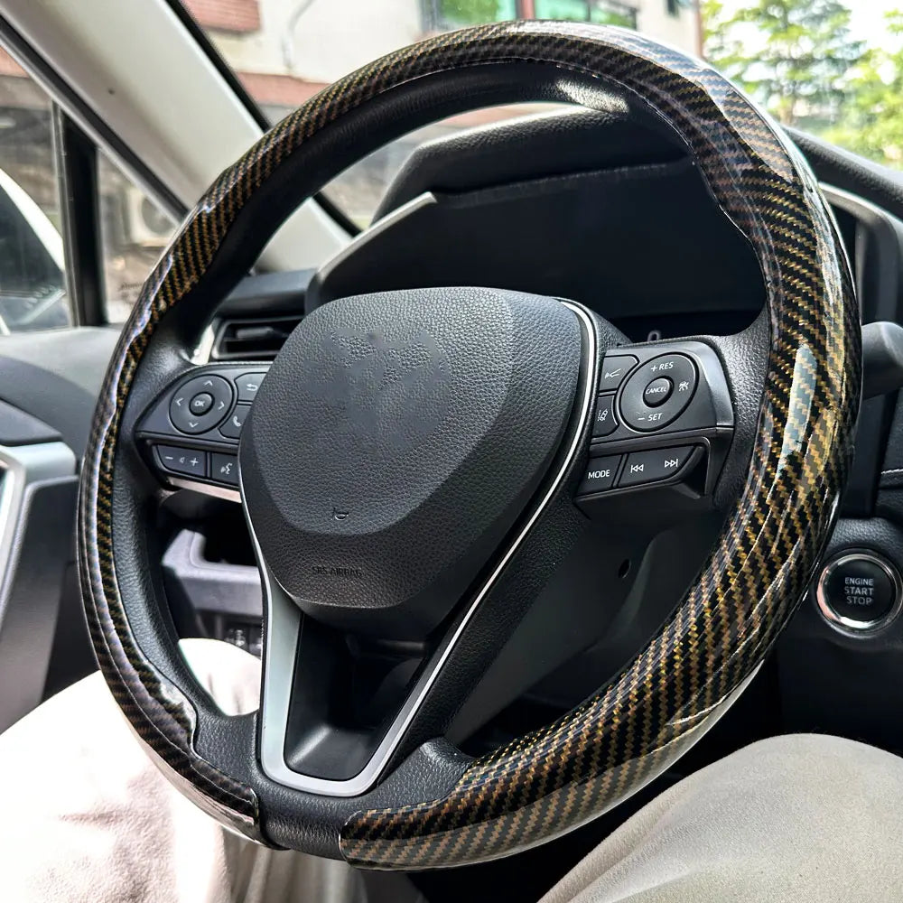 Nahaufnahme eines schwarzen Lenkrads mit einer Kohlefaser-Musterabdeckung im Auto