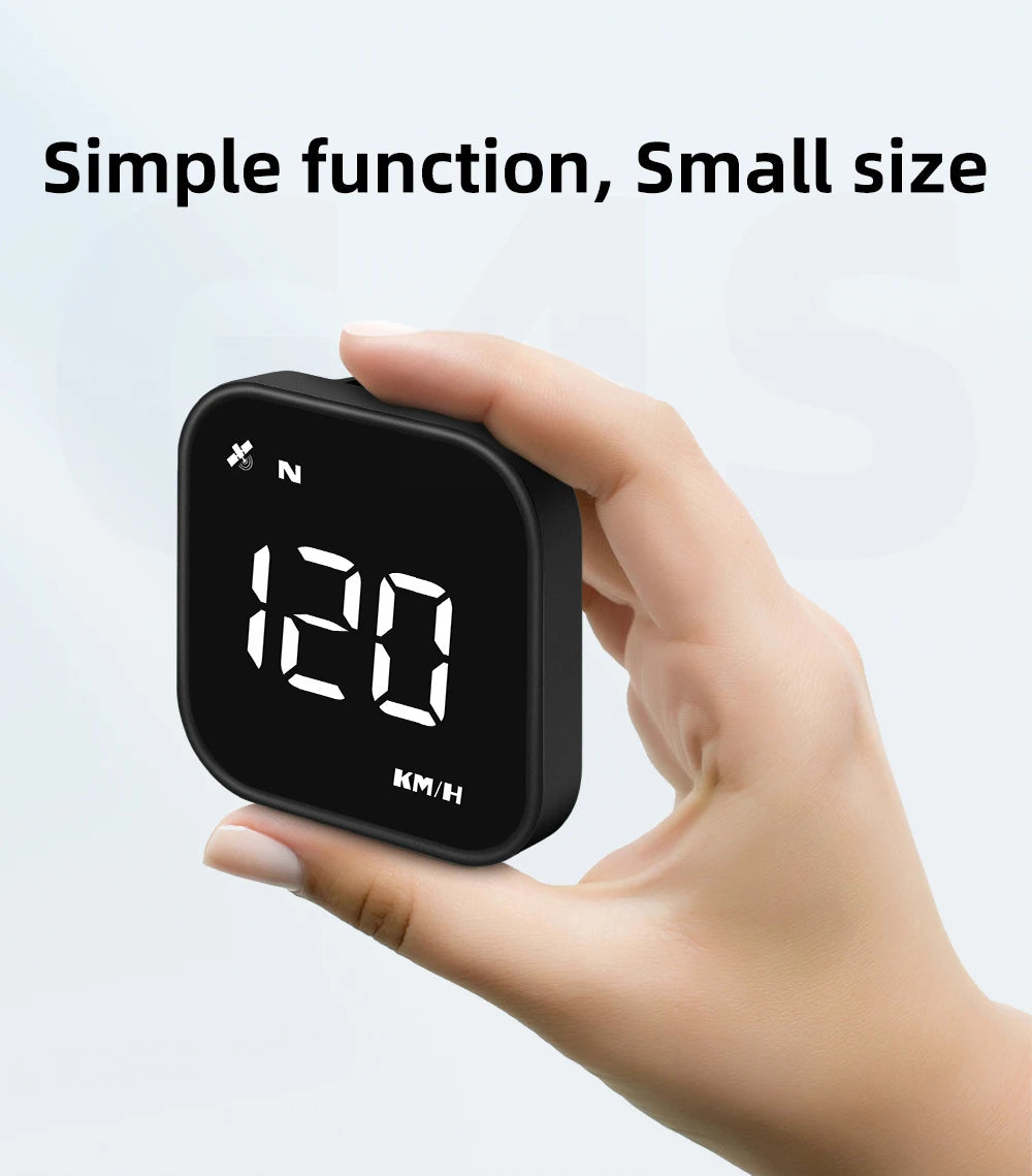 A hand holds a small, black GPS smart gauge head-up display device showing speed in km/h.