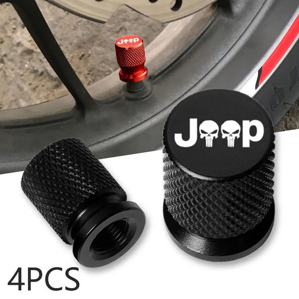 Four black Jeep skull tire valve caps and a valve stem fitting shown on an automotive wheel.