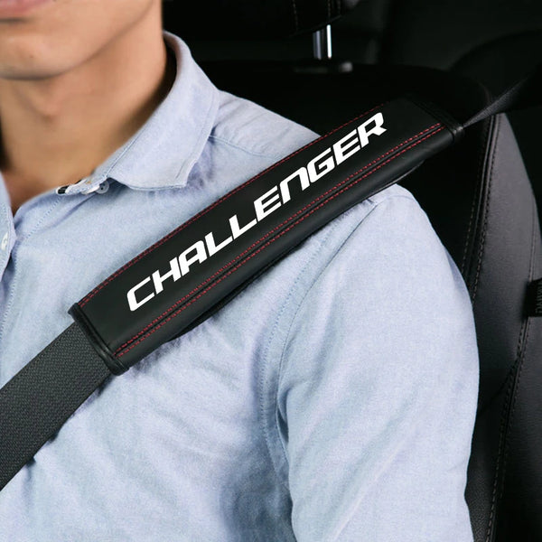 Un detalle de la correa del cinturón de seguridad de un asiento de coche, negro y rojo, sobre una camisa azul claro.