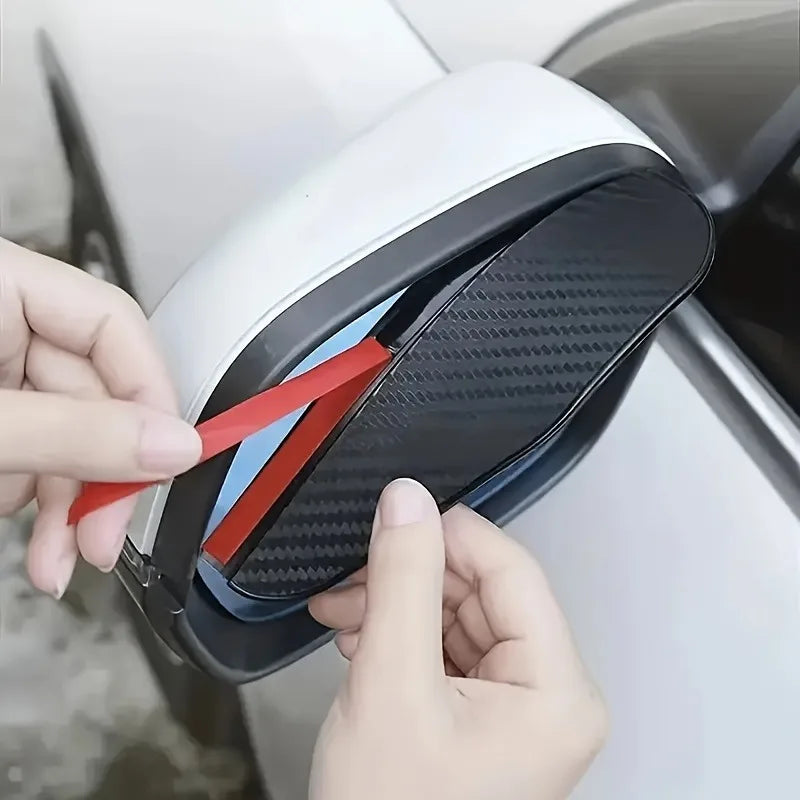 A hand is removing a black anti-fog textured rearview mirror cover from a white car interior.