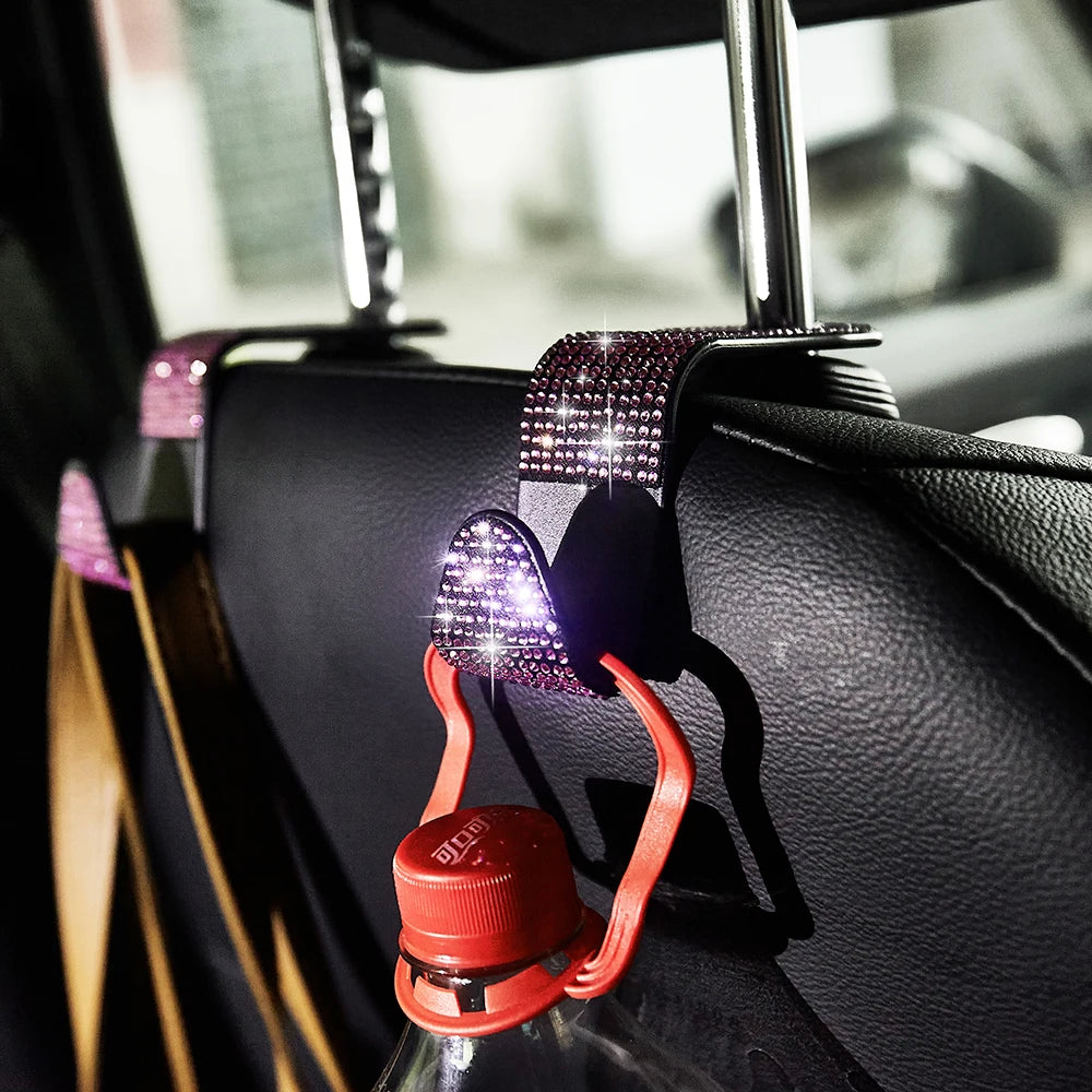 Close-up of dual artificial diamond car hooks in red and purple, mounted on a black car interior surface.