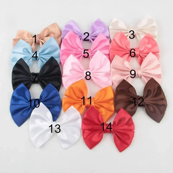 A collection of fourteen handmade silk hair bows in various shades of pink, peach, blue, and brown.