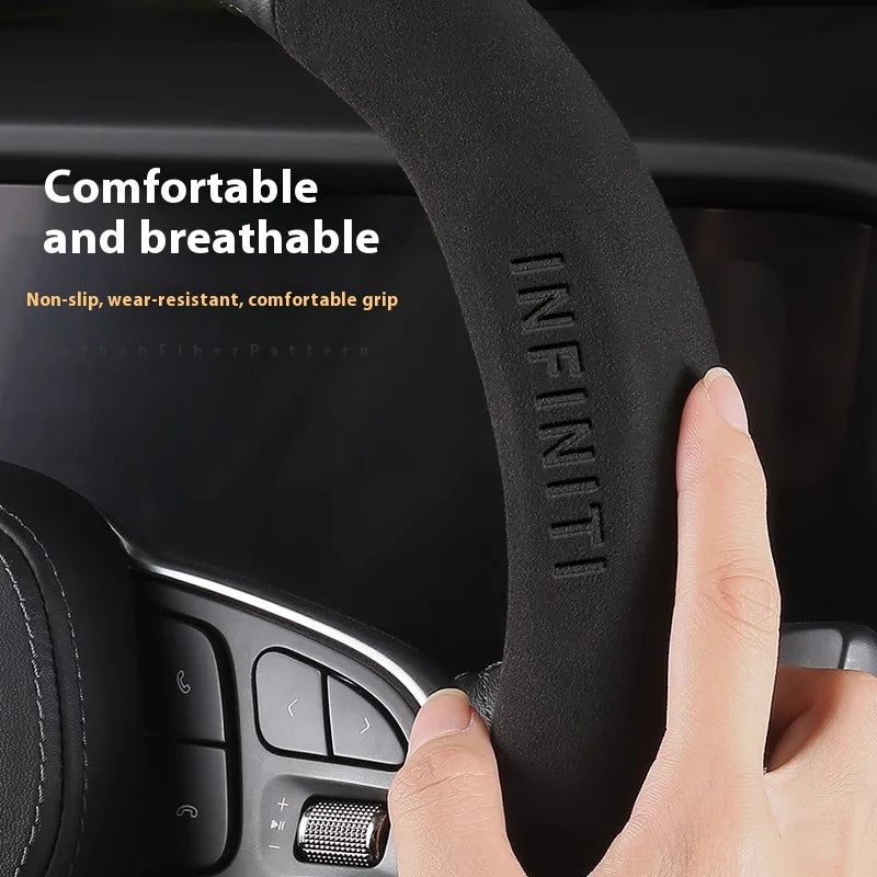 Close-up of a black steering wheel cover with the INFINITI logo, showing a hand gripping the breathable material.