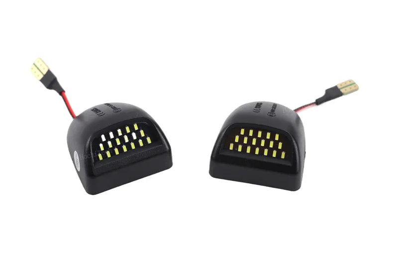 Un par de luces de matrícula LED de alta intensidad con carcasas negras y conectores eléctricos.
