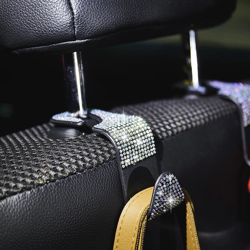 Close-up of black car hooks with dual artificial diamond accents and gold leather straps.