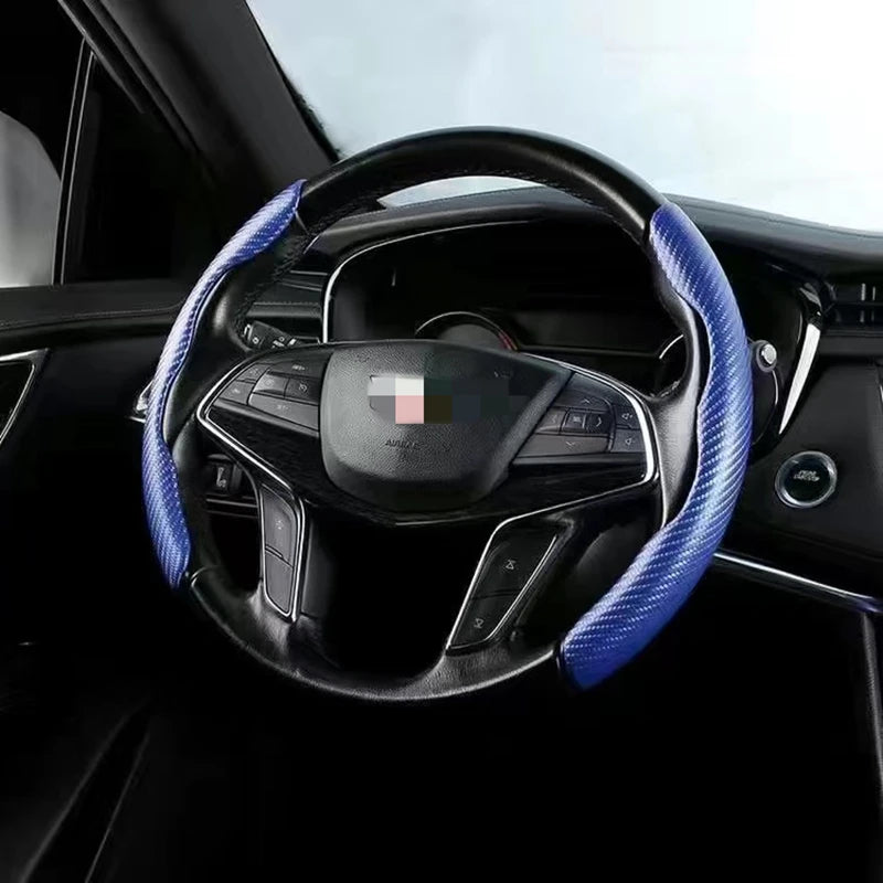 A black steering wheel with blue stitching and a carbon fiber-look cover is shown inside a car interior.
